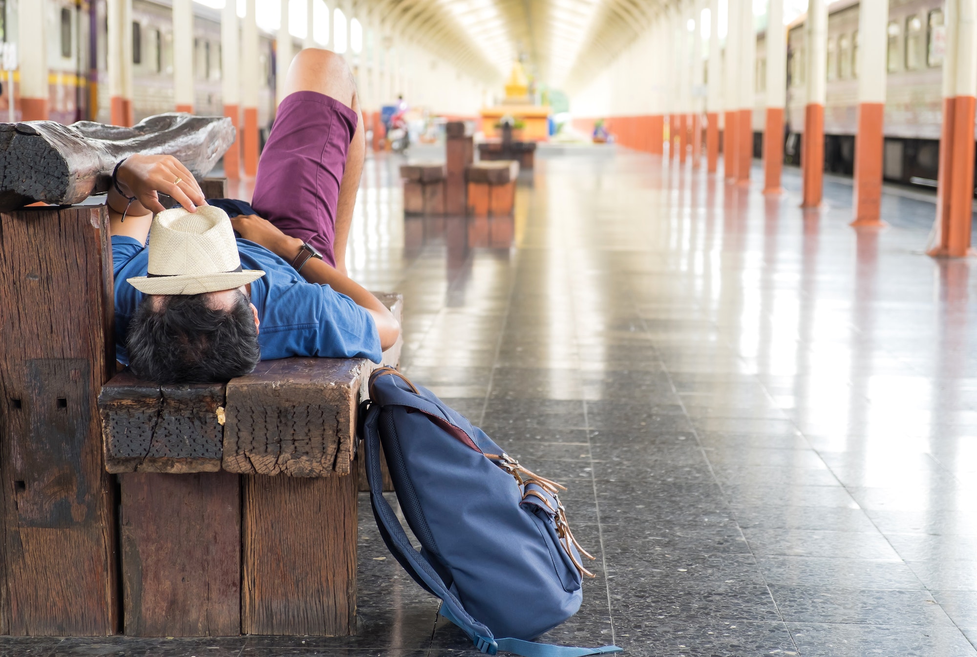 Travelers slept on chairs while waiting for the train,Hat on fac